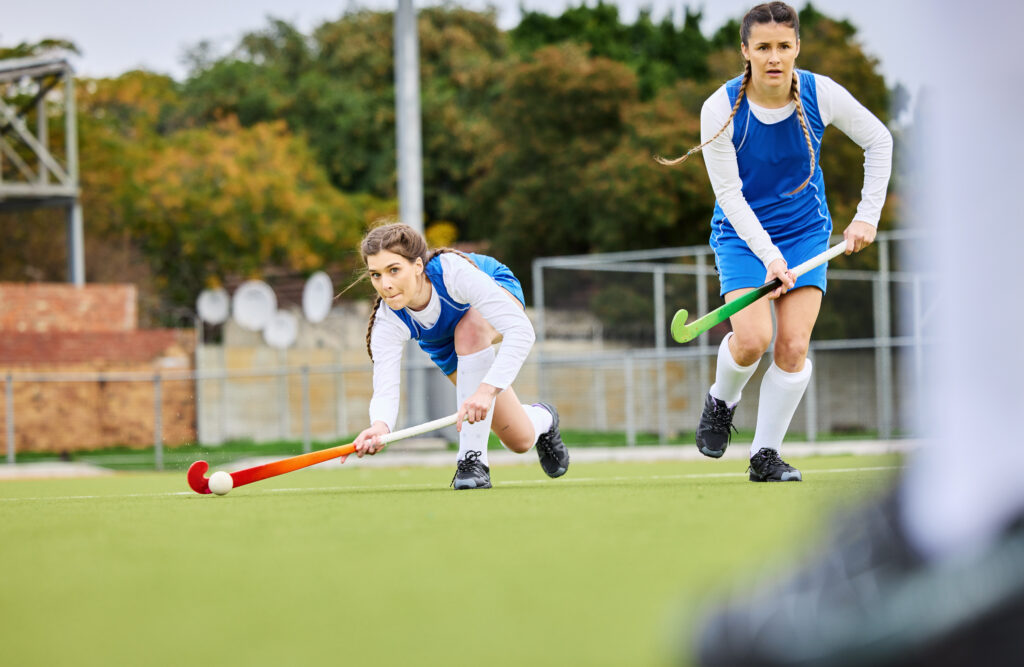 fitness, workout and female hockey players training for a game, match or tournament on an outdoor field. sports, exercise and young women playing at practice with a stick and ball on pitch at stadium